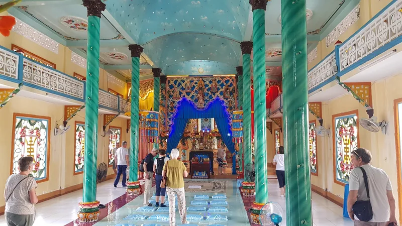Tourists walk beneath teal columns inside the ornately decorated Cao Dai temple in the Mekong Delta.